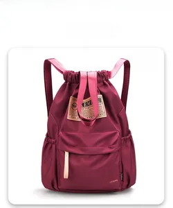 Vue de face d'un grand sac à dos en nylon bordeaux avec cordon de serrage et poches zippées