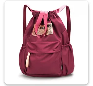 Détail de profil du sac à dos bordeaux en nylon avec cordon et poche frontale à rabat