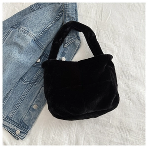 Detail der weichen schwarzen Kunstfell-Textur einer minimalistischen Tasche mit breitem Griff