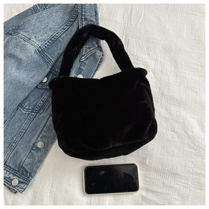 Flachbild einer schwarzen Plüsch-Tasche aus Kunstpelz mit breitem Griff auf weißem Stoff