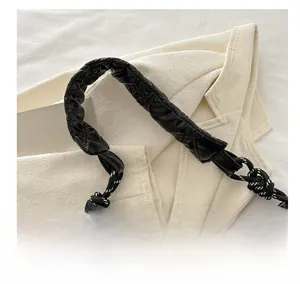Detail of black quilted puffer shoulder bag with a stylish woven rope knot on the handle