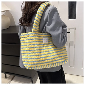 Detailansicht der gelb-blau gestreiften Plüschtasche mit einem quadratischen Stoffetikett