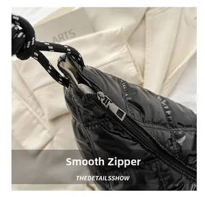 Detail shot of the smooth metal zipper and glossy quilted nylon fabric on the black bag