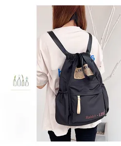 Détail du sac à dos noir en nylon avec cordon de serrage, poche zippée avant et poche latérale