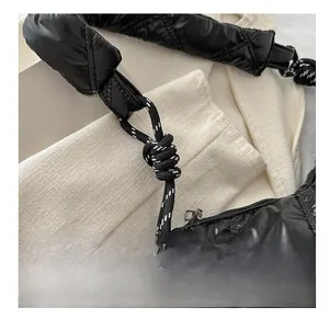 Close-up of black quilted puffer bag with glossy finish and knotted rope strap detail