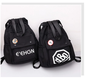 Dettaglio dello zaino nero in Oxford con coulisse, tasche e badge decorativi di moda