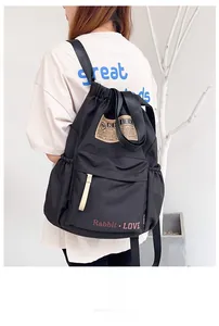 Détail du sac à dos en nylon noir à cordon avec logo vintage et lettrage rose lapin