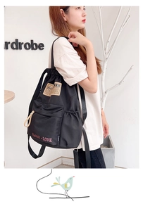 Détail du sac à dos en nylon noir avec cordon de serrage, poche latérale et écusson vintage