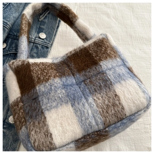 Detailansicht der flauschigen Kunstpelztextur auf einer blau-braun karierten Stofftasche
