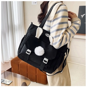 Dettaglio della borsa tote in nylon nero con orecchie di coniglio e pompon bianco