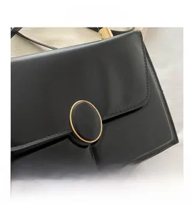 Detail of black faux leather handbag showing fine stitching and golden metal buckle
