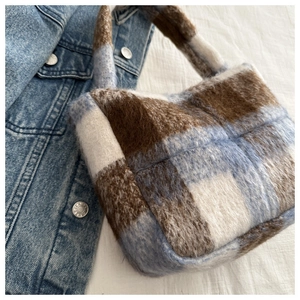 Detailaufnahme einer weichen Karo-Handtasche mit hellblauem und braunem Karomuster