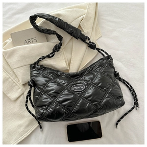Detail of black quilted shoulder bag with large diamond stitching and woven rope strap
