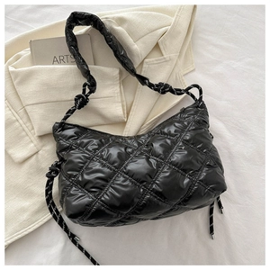 Detail of black quilted puffer bag with chic rhombic stitching and striped rope strap