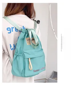 Détail du sac à dos vert menthe à cordon avec texte rouge et texture en nylon léger