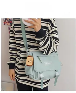 Détail de la besace en nylon vert menthe avec boucles en plastique et charme toast peluche