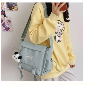 Détail du sac messager en nylon vert clair avec boucles blanches et breloque panda