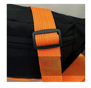 Close-up of a black nylon crossbody bag featuring a bright orange adjustable shoulder strap
