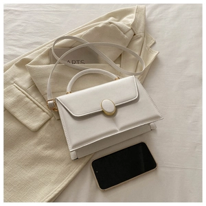 Close-up of matte cream white leather handbag featuring gold-toned hardware on beige blazer