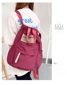Vue détaillée du sac à dos bordeaux en nylon avec cordon de serrage et poches latérales
