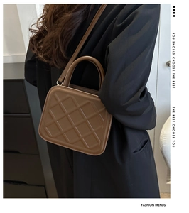Detailed view of the brown quilted crossbody bag with top handle and shoulder strap