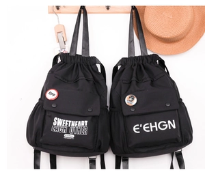 Dettaglio di zaini neri in oxford con coulisse, tasche con fibbia e stampe in stile street