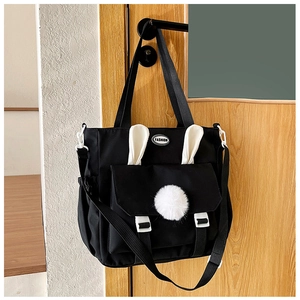 Dettaglio borsa a tracolla in nylon nero con orecchie di coniglio bianche e pompon