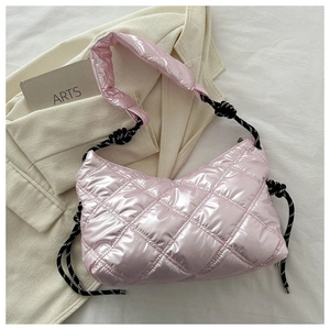 Pink quilted down tote bag with woven rope handle on an elegant off-white blazer
