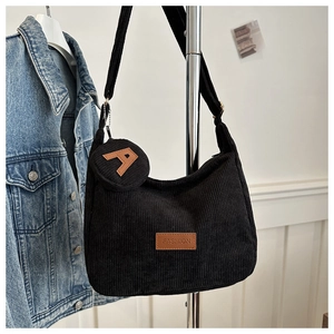 Detail of black corduroy hobo bag featuring a round coin purse and faux leather brand tag