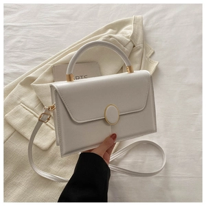 Detail of cream leather crossbody bag with gold buckle on a neutral blazer background