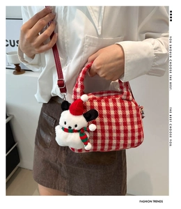Dettaglio borsa in maglia a quadri rosso e crema con ciondolo a cucciolo natalizio