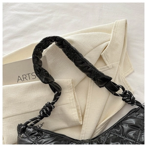 Close-up of black glossy quilted nylon bag featuring wide padded strap and braided cord knot