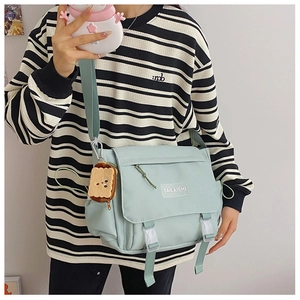 Détail du sac messager en nylon vert menthe avec boucles et porte-clé en peluche