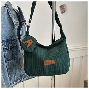Detail of dark green corduroy shoulder bag showing ribbed texture and mini round coin purse