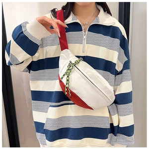 Detail view of red and white contrast waist bag with decorative woven cord on model