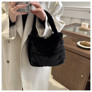 Detail einer flauschigen schwarzen Kunstpelz-Handtasche, die eine Frau im Trenchcoat trägt