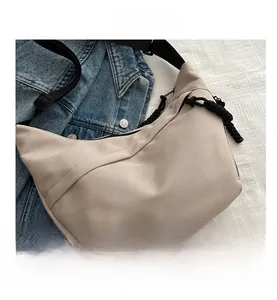 Detail view of beige crescent bag with adjustable wide strap and knotted zipper puller