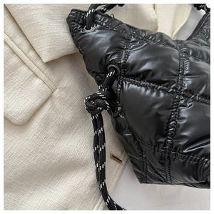 Detail of black quilted puffer bag with glossy finish and stylish braided rope strap
