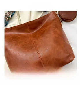 Macro detail of brown retro leather bag with ethnic embroidery strap and small pouch
