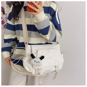 Détail du sac messager en nylon blanc avec sangle réglable et porte-clé peluche