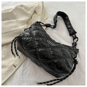 Detail of black glossy quilted down shoulder bag with woven drawstring and fashion patch