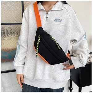 Detail of ergonomic black and orange nylon crossbody chest bag with neon zipper pulls