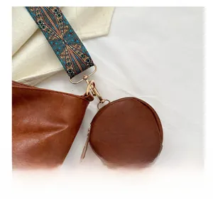 Detail of brown leather bag with a round coin purse and ethnic woven shoulder strap