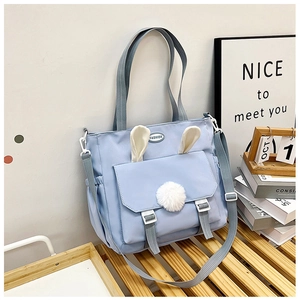 Dettaglio della borsa in nylon azzurro con orecchie di coniglio e pompon decorativo