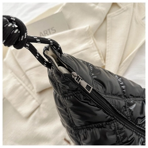 Detail of black quilted puffer bag with glossy finish and thick rope shoulder strap
