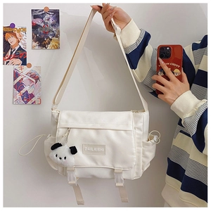 Détail du sac messager en toile blanc cassé avec boucle et breloque panda en peluche