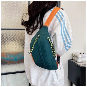 Detail of green and orange contrast chest bag with sturdy zippers and wide strap