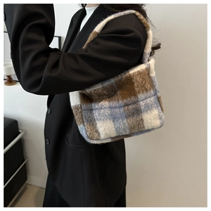 Detail der weichen karierten Plüschtasche mit braun-blauen Mustern auf schwarzem Anzug