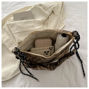 Interior detail of bronze quilted bag showing large capacity for phone and wallet