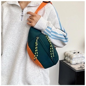 Detail of dark green and orange crossbody chest bag with decorative zipper cords